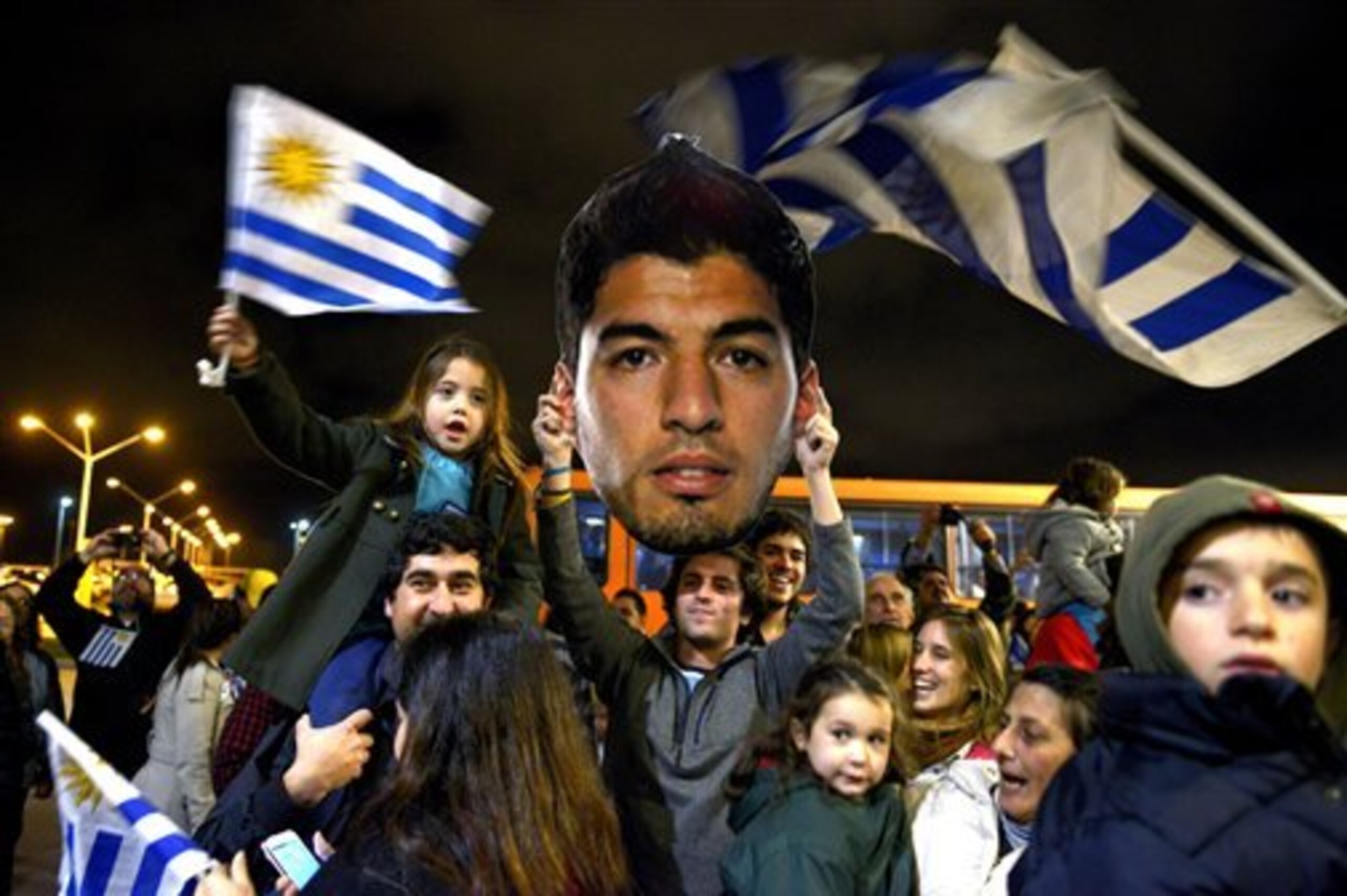 Fans of Uruguay's national soccer team await the arrival of Uruguay player Luis Suarez at Carrasco International Airport in the outskirts of Montevideo, Uruguay, Thursday, June 26, 2014. The Uruguay forward, widely regarded as one of the best players in the world, was banned by FIFA from all football for four months on Thursday for biting an Italian opponent in an incident that marred the team's victory and progression to the second round. (AP Photo/Matilde Campodonico)