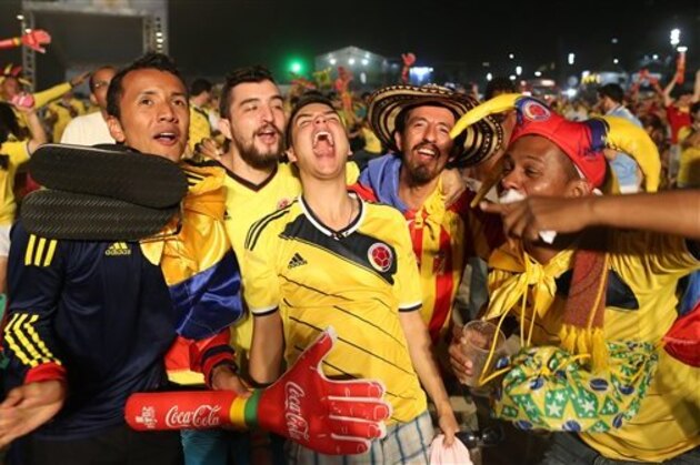 Colombia soccer fans celebrate the second goal scored by their team as they watch a live telecast of their team's World Cup against with Japan inside the FIFA Fan Fest area on Copacabana beach, in Rio de Janeiro, Brazil, Tuesday, June 24, 2014. Substitute James Rodriguez scored a brilliant goal and set up two more for Jackson Martinez as Colombia beat Japan 4-1 on Tuesday to confirm top spot in Group C and eliminate the Asian champions from the World Cup.  (AP Photo/Leo Correa)