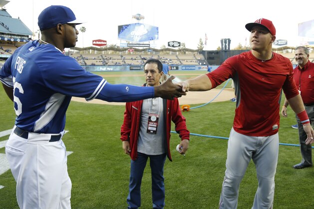 Los Angeles Dodgers' Yasiel Puig, left, shakes hands with Los Angeles Angels' Mike Trout, right, after they talked with jockey Victor Espinoza, center, before Espinoza threw out the first pitch for an exhibition baseball game in Los Angeles, Thursday, March 27, 2014. (AP Photo/Danny Moloshok)