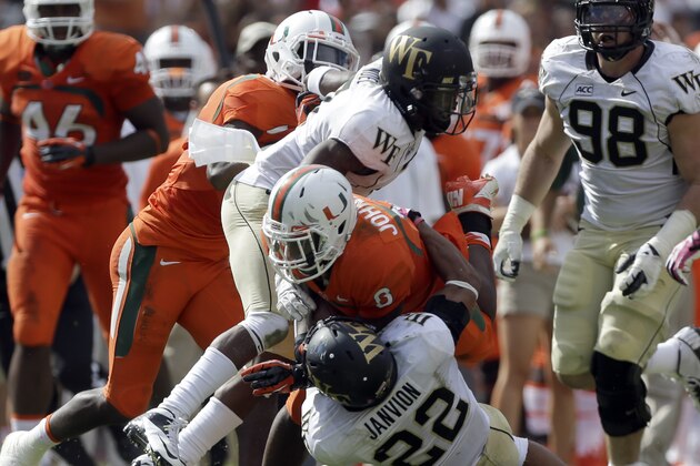 Wake Forest's Merrill Noel and Ryan Janvion (22) take down Miami's Duke Johnson (8)  during an NCAA college football game, Saturday, Oct. 26, 2013, in Miami Gardens, Fla. Miami won 24-21. (AP Photo/Alan Diaz)