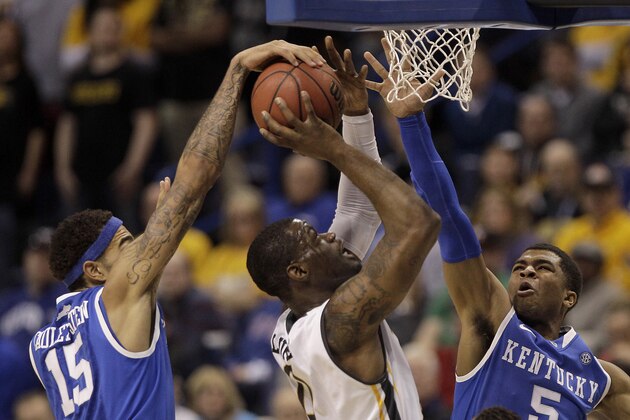 Wichita State's Chadrack Lufile (0) shoots under pressure from Kentucky's Willie Cauley-Stein (15) and Andrew Harrison (5) during the first half of a third-round game at the NCAA college basketball tournament Sunday, March 23, 2014, in St. Louis. (AP Photo/Charlie Riedel)