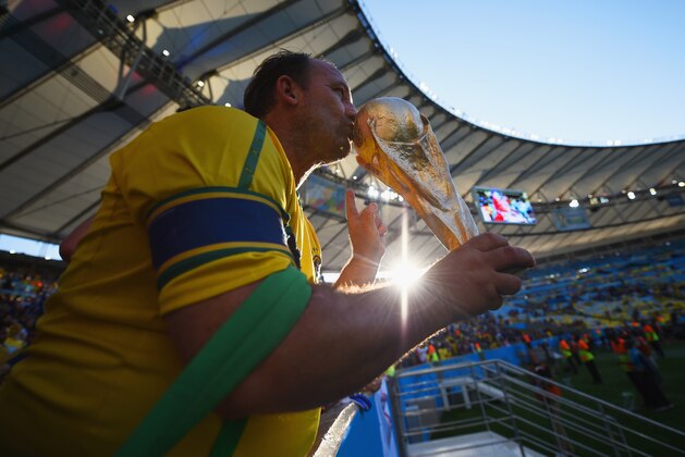 RIO DE JANEIRO, BRAZIL - JUNE 25: A fan kisses a replica of the World Cup trophy during the 2014 FIFA World Cup Brazil Group E match between Ecuador and France at Maracana on June 25, 2014 in Rio de Janeiro, Brazil.  (Photo by Matthias Hangst/Getty Images)
