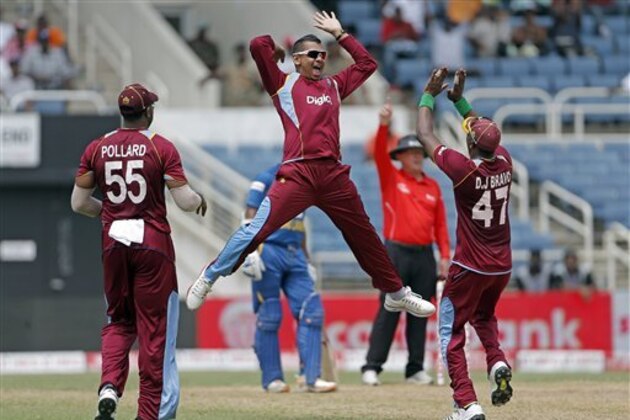 West Indies spin bowler Sunil Narine, center, jumps to high five his captain Dwayne Bravo, right, as teammate Kieron Pollard watches, after taking the wicket of Sri Lanka's opening batsman Mahela Jayawardene for 52 runs during their Tri-Nation Series cricket match in Kingston, Jamaica, Friday, June 28, 2013. (AP Photo/Andres Leighton)