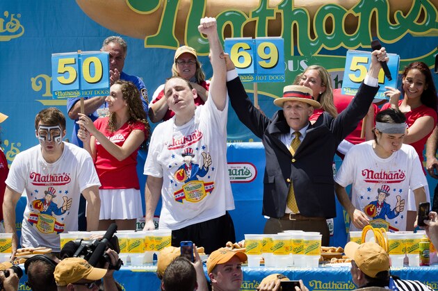 Joey Chestnut, center, wins the Nathan's Famous Fourth of July International Hot Dog Eating contest with a total of 69 hot dogs and buns, alongside Tim Janus, left, and Matt Stonie, right, at Coney Island, Thursday, July 4, 2013, in the Brooklyn borough of New York. (AP Photo/John Minchillo)