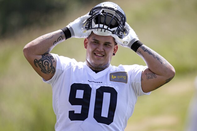 Seattle Seahawks' Jesse Williams pulls on his helmet at an NFL organized team activity football practice Monday, June 2, 2014, in Renton, Wash. (AP Photo/Elaine Thompson)