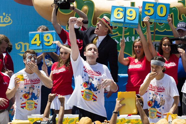 Joey Chestnut, center, wins the Nathan's Famous Fourth of July International Hot Dog Eating contest with a total of 69 hot dogs and buns, alongside Tim Janus, left, and Matt Stonie, right, Thursday, July 4, 2013 at Coney Island, in the Brooklyn borough of New York. With his record breaking victory, Chestnut brings home the mustard-colored belt for the seventh year. (AP Photo/John Minchillo)