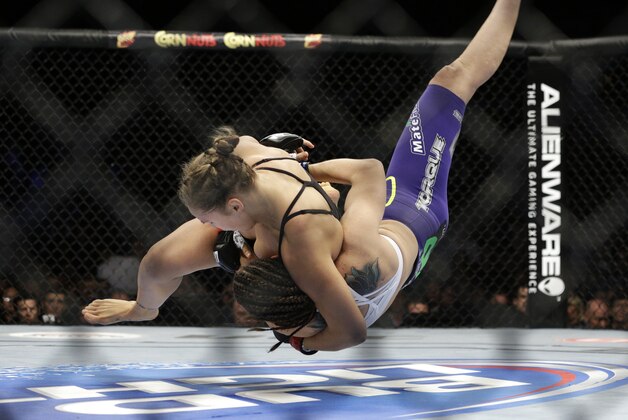 Ronda Rousey, left, takes down Alexis Davis during their women's mixed martial arts bantamweight title bout at UFC 175 on Saturday, July 5, 2014, in Las Vegas. (AP Photo/John Locher)
