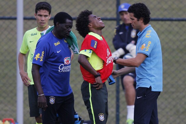Brazil's Willian receives the attention of the soccer team's physician, Rodrigo Lasmar, right, after getting hurt during a struggle for the ball with a teammate during a practice session at the Granja Comary training center in Teresopolis, Brazil, Saturday, July 5, 2014. Brazil will play in the semifinals of the 2014 Soccer World Cup on Tuesday, July 8. (AP Photo/Leo Correa)