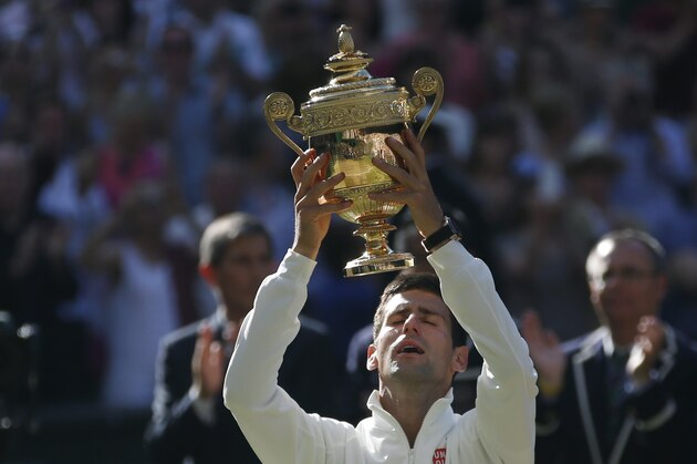 Novak Djokovic of Serbia holds up the trophy after defeating Roger Federer of Switzerland in the men's singles final at the All England Lawn Tennis Championships in Wimbledon, London, Sunday July 6, 2014. (AP Photo/Pavel Golovkin)