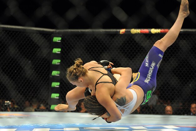 Jul 5, 2014; Las Vegas, NV, USA; Ronda Rousey (red gloves) takes down Alexis Davis (blue gloves) during the first round of a bantamweight fight at Mandalay Bay Events Center. Mandatory Credit: Stephen R. Sylvanie-USA TODAY Sports
