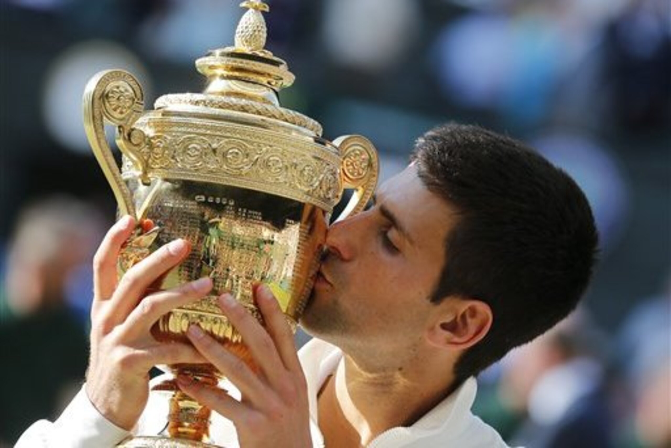 Novak Djokovic of Serbia kisses the trophy after defeating Roger Federer of Switzerland in the men's singles final at the All England Lawn Tennis Championships in Wimbledon, London, Sunday July 6, 2014. (AP Photo/Ben Curtis)
