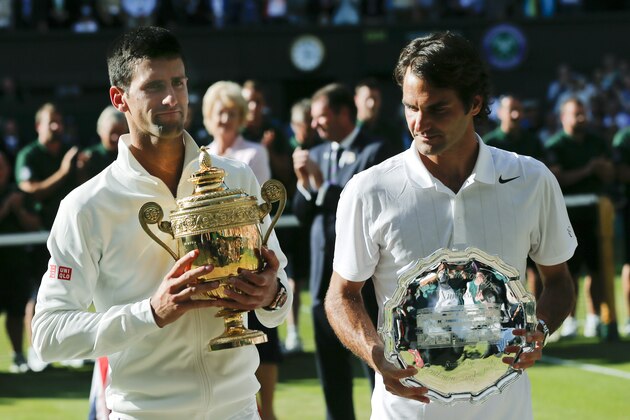 Serbia's Novak Djokovic, left, holds his trophy after defeating Switzerland's Roger Federer, right, in the men's singles final match at the All England Lawn Tennis Championships in Wimbledon, London, Sunday, July 6, 2014. (AP Photo/Ben Curtis)