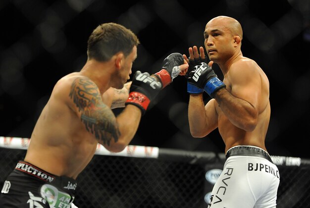 Jul 6, 2014; Las Vegas, NV, USA; BJ Penn (blue gloves) blocks a punch by Frankie Edgar (red gloves) during a featherweight fight at Mandalay Bay Events Center. Mandatory Credit: Stephen R. Sylvanie-USA TODAY Sports