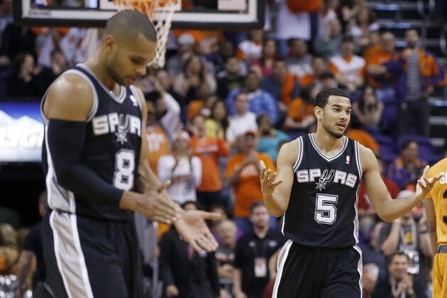 San Antonio Spurs' Patty Mills (8), of Australia, and Cory Joseph (5) walk back to the team bench as Phoenix Suns' Marcus Morris (15), Archie Goodwin (20), Markieff Morris (11) and Ish Smith (3) celebrate a score by Goodwin during the second half of an NBA basketball game, Friday, Feb. 21, 2014, in Phoenix. The Suns defeated the Spurs 106-85. (AP Photo/Ross D. Franklin)