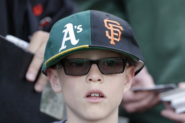 A fan wears a hat with logos for both the Oakland Athletics and the San Francisco Giants before an exhibition baseball game between the Giants and the Athletics in San Francisco, Thursday, March 27, 2014. (AP Photo/Jeff Chiu)