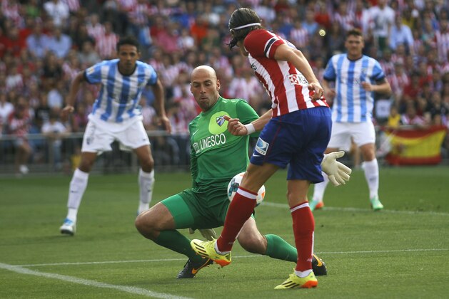 Atletico's Filipe Luis, right, vies for the ball with Malaga's goalkeeper Willy Caballero, left,  during their Spanish La Liga soccer match at the Vicente Calderon stadium in Madrid, Spain, Sunday, May 11, 2014. (AP Photo/Gabriel Pecot)