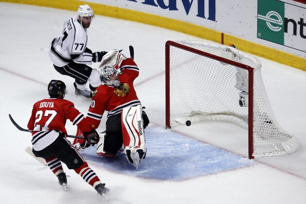 Los Angeles Kings center Jeff Carter (77) scores a goal against Chicago Blackhawks goalie Corey Crawford (50) as the Blackhawks defenseman Johnny Oduya (27) watches during the first period in Game 7 of the Western Conference finals in the NHL hockey Stanley Cup playoffs Sunday, June 1, 2014, in Chicago. (AP Photo/Charles Rex Arbogast)