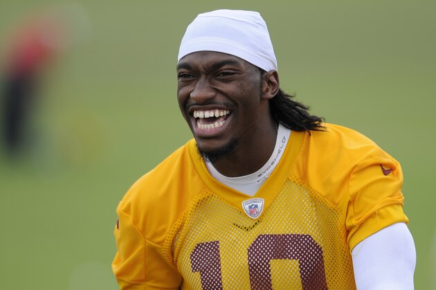 Washington Redskins quarterback Robert Griffin III (10) reacts as he walks towards cameras after an NFL football minicamp, Wednesday, June 18, 2014, in Ashburn, Va. (AP Photo/Nick Wass)