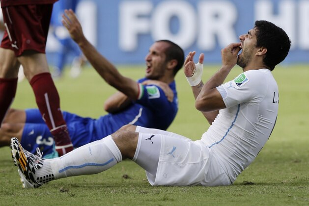 FILE - In this June 24, 2014 file photo, Uruguay's Luis Suarez holds his teeth after biting Italy's Giorgio Chiellini's shoulder during the group D World Cup soccer match between Italy and Uruguay at the Arena das Dunas in Natal, Brazil. On Thursday, June 26, 2014, FIFA banned Suarez for 9 games and 4 months for biting his opponent at the World Cup. (AP Photo/Ricardo Mazalan, File)