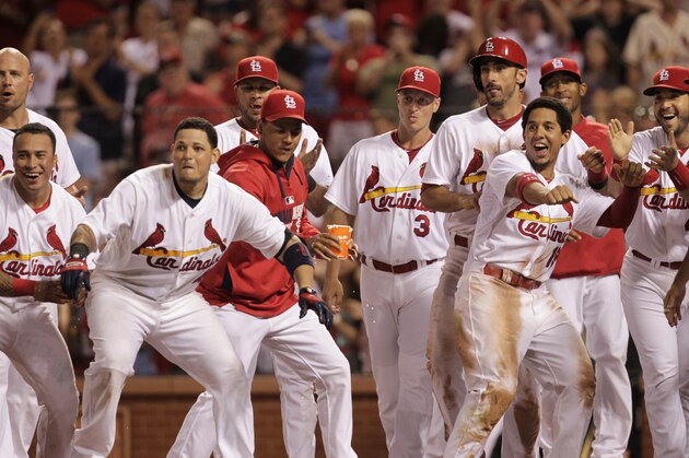 St. Louis Cardinals' Yadier Molina, second from left, and his teammates surround home plate as they wait for Matt Adams after he hit a two-run-walk-off home run in the ninth inning of a baseball game against the Pittsburgh Pirates, Monday, July 7, 2014, in St. Louis. The Cardinals won 2-0. (AP Photo/Tom Gannam)