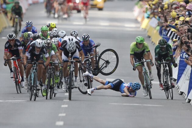 Andrew Talansky of the U.S. crashes as the pack with stage winner Italy's Matteo Trentin, foreground left, sprints towards the finish line during the seventh stage of the Tour de France cycling race over 234.5 kilometers (145.7 miles) with start in Epernay and finish in Nancy, France, Friday, July 11, 2014. (AP Photo/Peter Dejong)