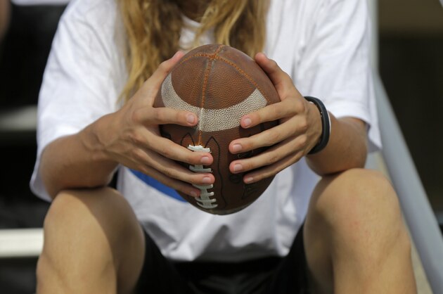 A camper holds a football as he waits for his group to be called on the first day at the Manning Passing Academy on the Nicholls State University campus in Thibodaux, La., Thursday, July 10, 2014. (AP Photo/Gerald Herbert)