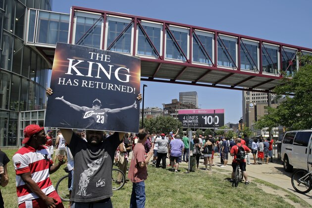 Graphic designer Alvin Smith holds up a poster across the street from the Quicken Loans Arena in Cleveland, Friday, July 11, 2014, heralding the return of NBA basketball star LeBron James. James, who left the Cleveland Cavaliers four years ago to join the Miami Heat, announced earlier he would return to the Cavaliers. (AP Photo/Mark Duncan)