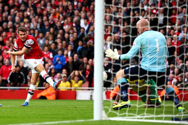 LONDON, ENGLAND - OCTOBER 19:  Aaron Ramsey of Arsenal (C) shoots past goalkeeper John Ruddy of Norwich City to score their third goal during the Barclays Premier League match between Arsenal and Norwich City at Emirates Stadium on October 19, 2013 in London, England.  (Photo by Paul Gilham/Getty Images)