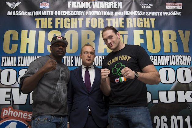 Boxers Dereck Chisora, left, and Tyson Fury stand either side of Francis Warren, son of promoter Frank Warren at a press conference to publicise their forthcoming world title eliminator fight, Manchester, England, Thursday March 20, 2014. The fight will take place on 26 July in Manchester with the winner possibly going on to challenge IBF, WBA and WBO heavyweight champion Wladimir Klitschko. (AP Photo/Jon Super)
