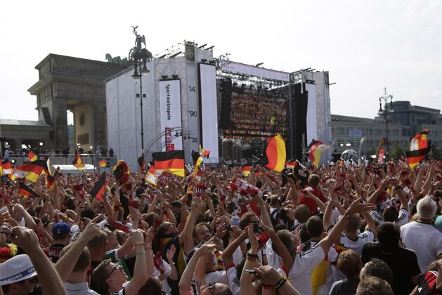 Fans take pictures of the plane with the German team on board that flies over the stage at the Brandenburg gate prior to the arrival of the German national soccer team in Berlin Tuesday, July 15, 2014. Germany beat Argentina 1-0 on Sunday to win its fourth World Cup title.  (AP Photo/Petr David Josek)