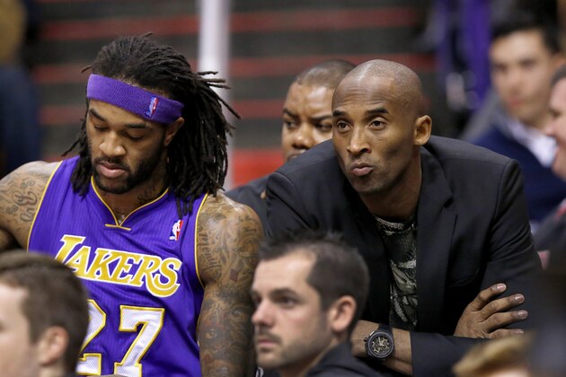 Injjured Los Angeles Lakers player Kobe Bryant, right, sits on the end of the team bench next to Jordan Hill, left, during the first half of an NBA basketball game against the Phoenix Suns on Wednesday, Jan. 15, 2014, in Phoenix. (AP Photo/Ross D. Franklin)