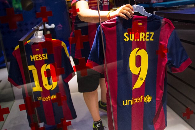 BARCELONA, SPAIN - JULY 12:  An employee hangs a Luis Suarez shirt next to a Leo Messi shirt after printing his name and number on it at the FC Barcelona official store on July 12, 2014 in Barcelona, Spain.  (Photo by David Ramos/Getty Images)