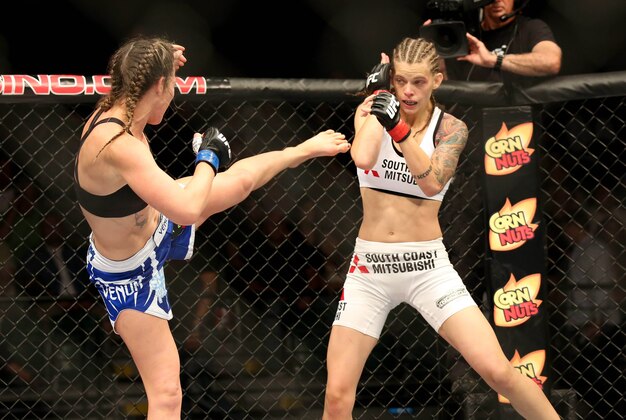 Jul 16, 2014; Atlantic City, NJ, USA; Jessamyn Duke (red gloves) blocks a kick by Leslie Smith (blue gloves) during a women's bantamweight bout at Revel Casino. Mandatory Credit: Bill Streicher-USA TODAY Sports
