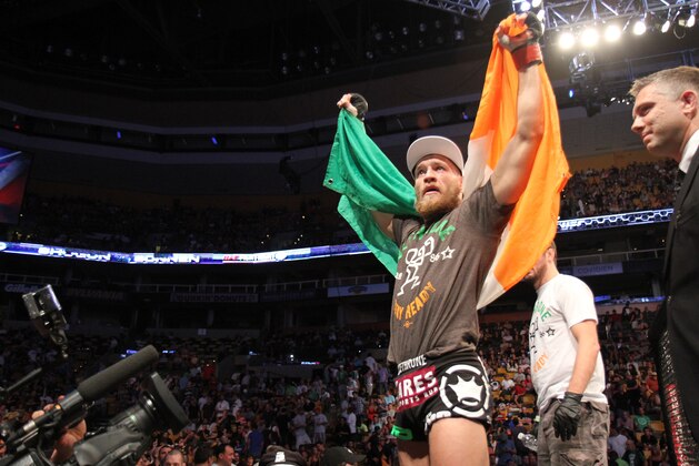Conor McGregor, of Ireland, leaves the ring draped in an Irish flag after beathing Max Holloway in their UFC on Fox Sports 1 mixed martial arts bout in Boston, Saturday, August 17,2013. McGregor won via unanimous decision. (AP Photo/Gregory Payan)