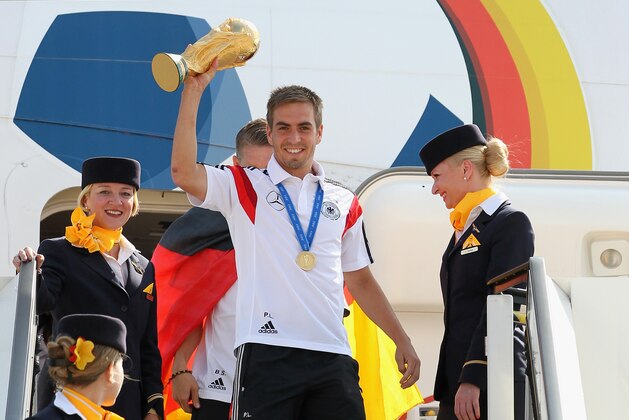 Germany's  Philipp Lahm  lifts the trophy at the  the arrival of the German national soccer team from Brazil  at Tegel airport in Berlin, Tuesday July 15, 2014.   Germany beat Argentina 1-0 on Sunday to win its fourth World Cup title. (AP Photo/ Karina Hessland,pool)