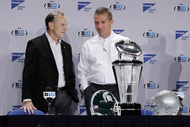 Michigan State head coach Mark Dantonio, left, talks with Ohio State head coach Urban Meyer during a news conference for the Big Ten Conference championship NCAA college football game Friday, Dec. 6, 2013, in Indianapolis. Ohio State will play Michigan State, Saturday for the championship. (AP Photo/Darron Cummings)