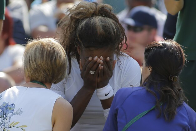 Court officials talk to Serena Williams of the U.S as she and Venus Williams retire after 3 games from their women's doubles match against Kristina Barrois of Germany and Stefanie Voegele of Switzerland at the All England Lawn Tennis Championships in Wimbledon, London, Tuesday July 1, 2014. (AP Photo/Pavel Golovkin)