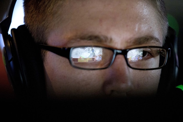 In this July 11, 2014 photo, a video screen is reflected in the glasses of Steven