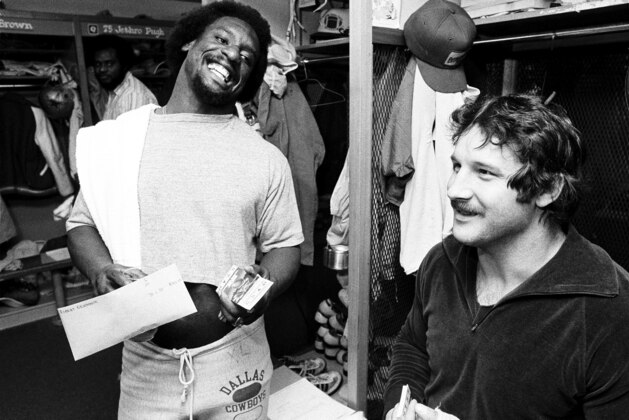 Robert Newhouse, Dallas Cowboys' fullback, left, shows his Super Bowl tickets to defensive tackle Randy White, in the Dallas locker room, Tex., Jan. 13, 1979. Randy jokingly accused Newhouse of getting more than his share. Cowboys meet Pittsburgh in the Super Bowl Jan. 21.  (AP Photo/Pete Leabo)