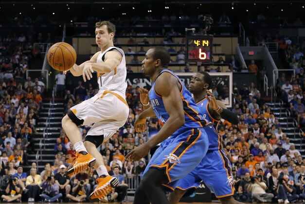 Phoenix Suns guard Goran Dragic (1), of Slovenia, dishes off as Oklahoma City Thunder forward Serge Ibaka, right, of Congo, defends, during the first half of an NBA basketball game on Sunday, April 6, 2014, in Phoenix. The Suns won 122-115. (AP Photo/Matt York)