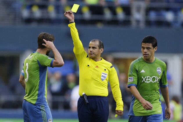 Seattle Sounders' Brad Evans, left, is shown a yellow card by referee Baldomero Toledo, center, as Sounders' Gonzalo Pineda, right, looks on, Wednesday, May 7, 2014, in the first half of an MLS soccer match in Seattle. (AP Photo/Ted S. Warren)