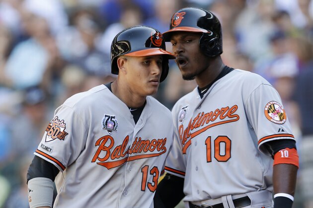 Baltimore Orioles' Adam Jones, right, greets Manny Machado after Machado hit a sacrifice fly that scored Jones in the 10th inning of a baseball game, Sunday, July 27, 2014, in Seattle. The Orioles won 3-2.  (AP Photo/Ted S. Warren)