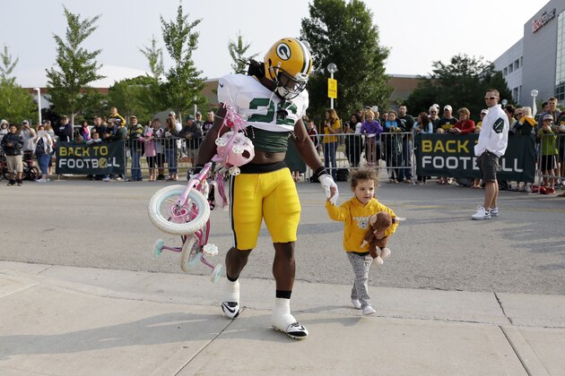 Green Bay Packers’ DuJuan Harris carries the bike of a fan to NFL football training camp Monday, July 28, 2014, in Green Bay, Wis. (AP Photo/Morry Gash)