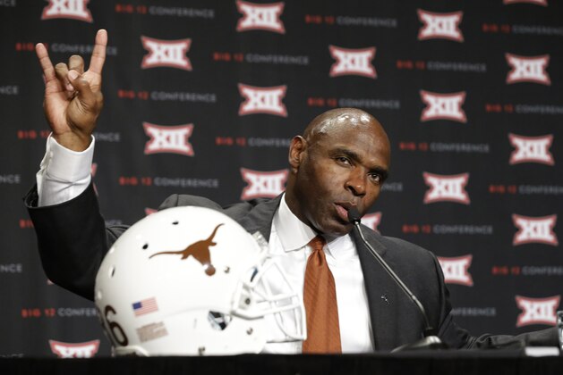 Texas head coach Charlie Strong gives a hook 'em horns hand gesture to demonstrate student celebrating rules for his athletes while speaking to the media at the Big 12 Conference NCAA college football media days in Dallas, Tuesday, July 22, 2014. (AP Photo)