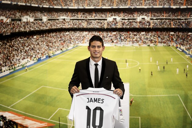 New Real Madrid player James Rodriguez, from Colombia, holds his new shirt and poses for photographers during his official presentation at the Santiago Bernabeu stadium in Madrid, Spain, Tuesday, July 22, 2014, after signing for Real Madrid. Real Madrid have signed Rodriguez from Monaco on a six-year contract. (AP Photo/Daniel Ochoa de Olza)