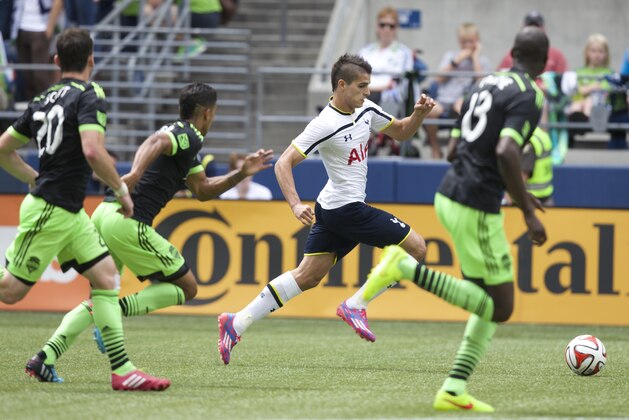 Tottenham Hotspur's Erik Lamela, second from left, dribbles the ball upfield as Seattle Sounders' Djimi Traore, far right, DeAndre Yedlin, second from left, and Zach Scott defend during a friendly soccer match in Seattle, Saturday, July 19, 2014. The match ended in a 3-3 draw. (AP Photo/Stephen Brashear)