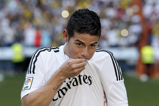 New Real Madrid player James Rodriguez, from Colombia, kisses Real's emblem of his shirt during his official presentation at the Santiago Bernabeu stadium in Madrid, Spain, Tuesday, July 22, 2014, after signing for Real Madrid. Real Madrid have signed Rodriguez from Monaco on a six-year contract,  (AP Photo/Daniel Ochoa de Olza)