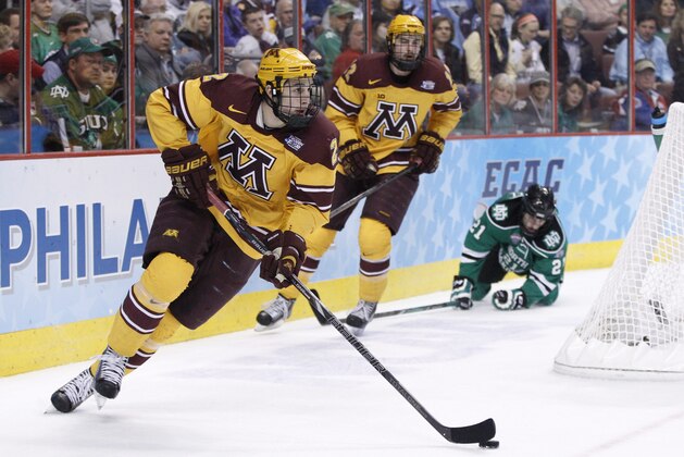 Minnesota's Brady Skjei, left, brings the puck from behind the goal with Justin Holl, center, and North Dakota's Brendan O'Donnell, right, behind him during the first period of an NCAA men's college hockey Frozen Four tournament game, Thursday, April 10, 2014, in Philadelphia. Minnesota won 2-1. (AP Photo/Chris Szagola)