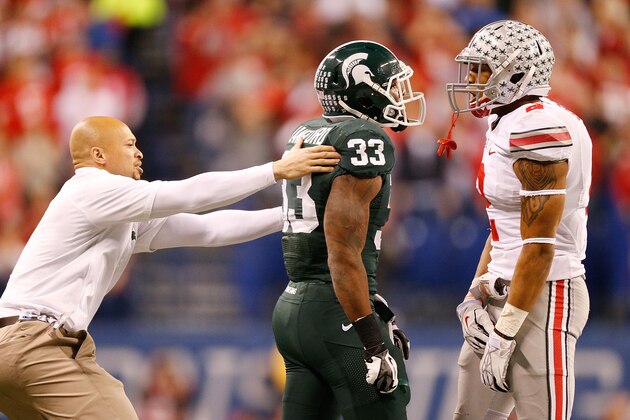 INDIANAPOLIS, IN - DECEMBER 07:  Assistant strength and conditioning coach Lorenzo Guess pulls back Jeremy Langford #33 of the Michigan State Spartans before tempers flare with Christian Bryant #2 of the Ohio State Buckeyes during the Big 10 Conference Championship Game at Lucas Oil Stadium on December 7, 2013 in Indianapolis, Indiana.  (Photo by Gregory Shamus/Getty Images)