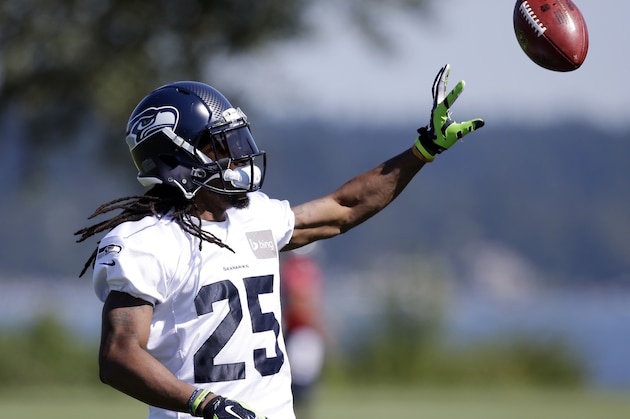 Seattle Seahawks' Richard Sherman tosses the ball during a drill at an NFL football camp practice on Saturday, July 26, 2014, in Renton, Wash. (AP Photo/Elaine Thompson)